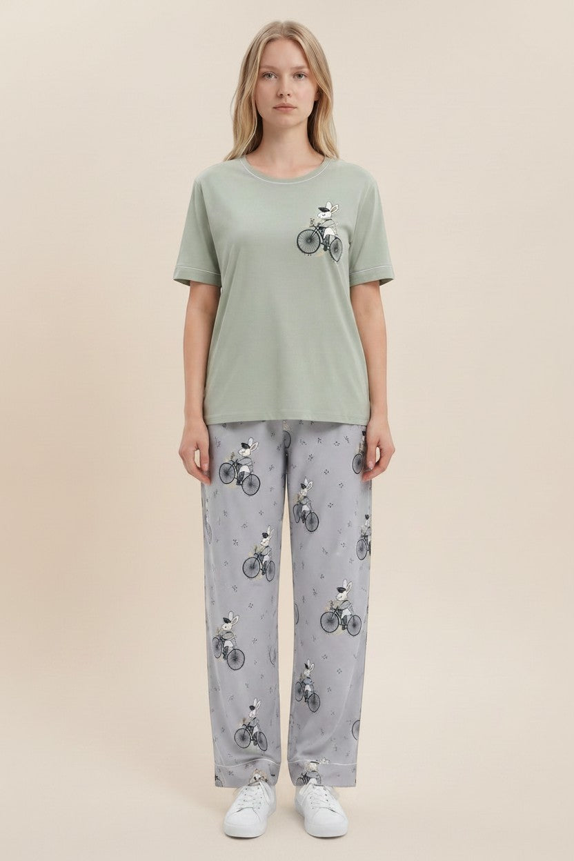 pyjama olive cotton pyjama set with rabbit on bicycle print worn by a blonde model against a neutral background